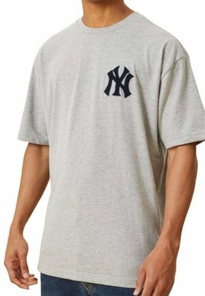 T-shirt en coton gris à manches courtes, avec un logo des Yankees bleu marine sur le côté gauche de la poitrine. Coupe décontractée avec un col rond.