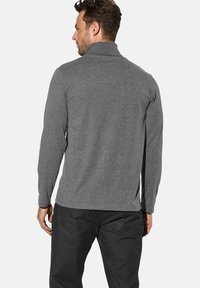 Grauer pullover mit langen Ärmeln und Kragen, aus weichem Material gefertigt. Verfügt über eine entspannte Passform und dezente Nähte auf der Rückseite.