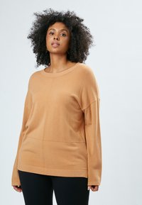 Lysebrune oversized sweater med rund halsudskæring, lange ærmer og vandrette sømme. Blød tekstur, simpelt design og afslappet pasform.
