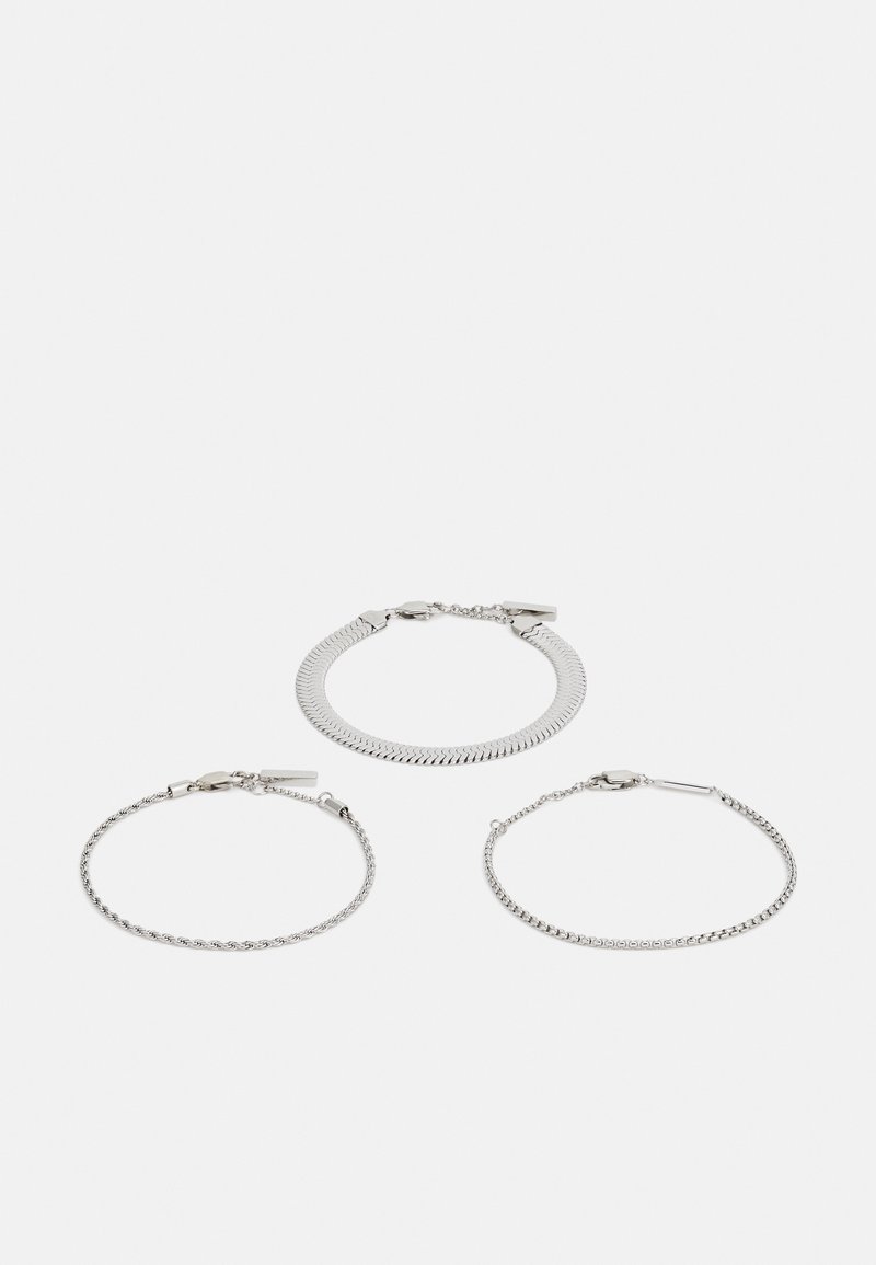 Ensemble de trois bracelets en argent présentant des designs variés : une chaîne à chevrons plate, une chaîne à corde tordue et une délicate chaîne à maillons ronds.