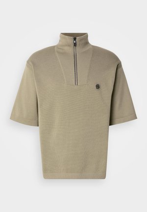 Short-sleeve, olive green polo with a high collar and half zip, featuring a texture knit and a small logo on the left chest.