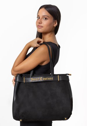Black suede handbag with leather accents, featuring gold "Juicy Couture" logo on the front, two sturdy handles, and a spacious design.