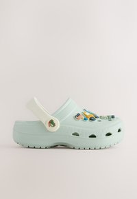 Light blue clog-style shoe with heel strap and colorful cartoon vehicle charms attached on top.