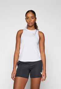 Hvit ermeløs treningstopp med rund hals, med en svart logo på brystet; kombinert med svarte shorts. Glatt stoff, tettsittende design.