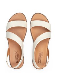 Sandalias de cuero beige claro con correas cruzadas, plantilla acolchada marrón, textura similar al ante y una correa trasera para mayor soporte.