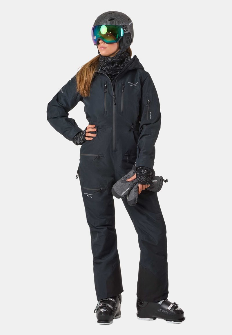 Schwarzer, einteiliger Skianzug aus wasserdichtem Material mit mehreren Reißverschlusstaschen und figurnahem Design. Zubehör umfasst Handschuhe und eine Skibrille.