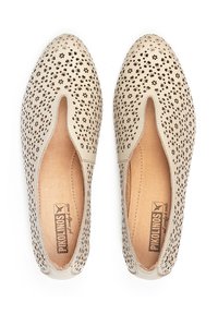Chaussures slip-on en cuir perforé beige avec des motifs floraux et un bout arrondi. Doublure intérieure lisse et semelle plate, avec un branding discret.