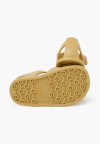 Sandalias de goma amarillas con una suela texturizada ondulada y correas ajustables, diseñadas para la comodidad y durabilidad. Hechas en España.