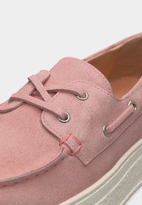 Ροζ σουέντ αθλητικό παπούτσι τύπου μοκασίνι με λευκή καουτσουκό καρίνα και δερμάτινα κορδόνια περασμένα από ασημένια στεφάνια.
