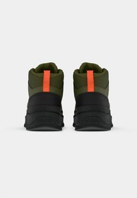 Grønne og svarte høyde sneakers med en teksturert overdel, med en oransje hælløkke og en polstret såle.