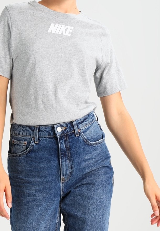 Grå bomulls-t-shirt med en vit "NIKE"-logotyp, kombinerad med högmidjade blå denimjeans med knappstängning och framfickor.