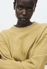Maglione a maglia giallo senape con scollo a girocollo rigato e maniche lunghe, caratterizzato da una vestibilità comoda e una texture morbida.