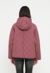 Μπουφάν από καπιτονέ βουργουνδί ύφασμα με κουκούλα, με κουτίσιο σιλουέτα, υφή ύφασμα και διαγώνιο σχέδιο στην πλάτη.