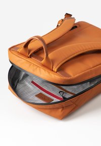 Oranje leren rugzak, met een grote ritssluiting, zachte gewatteerde banden en een interieur met een ruitpatroon en een rode ritszak.