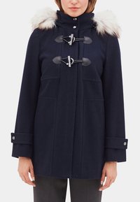 Navy blue wool coat featuring a fur-lined hood, toggle closures, two front pockets, and buttoned cuffs. Smooth texture with a structured design.