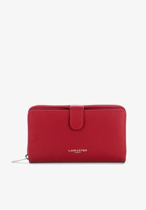 Red leather wallet with a smooth texture, zip closure, snap button, and embossed "Lancaster Paris" logo on the front. Compact rectangular shape.