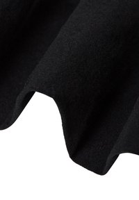 Svart tyg med en mjuk, texturerad yta, draperad i mjuka vågor, som uppvisar en matt finish och en jämn färg genom hela ytan.