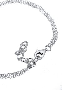 Hopeinen ketjurannekoru, jossa on toisiinsa lukittuvat lenkit, hummeri-soljella ja hieno ketjurakenne. Minimalistinen design kiillotetulla pinnalla.