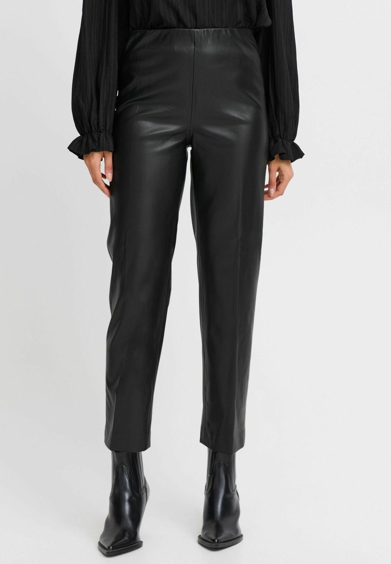 Pantaloni in pelle nera con una vestibilità slim, caratterizzati da una texture liscia e una vita alta. Abbinati a stivali neri alla caviglia a punta.