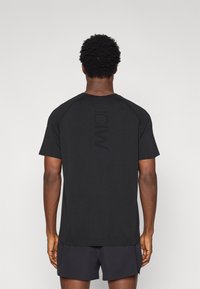 Μαύρο κοντομάνικο T-shirt με στρογγυλή λαιμόκοψη και ραγκλάν μανίκια. Φέρει διακριτικό λογότυπο "ICMI" με ματ φινίρισμα στο πίσω μέρος. Ομαλή υφή υφάσματος.