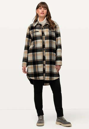Chaqueta de camisa a cuadros en tonos beige, negro y naranja. Con cierre de botones en el frente, dos bolsillos en el pecho y un dobladillo trasero ligeramente más largo.