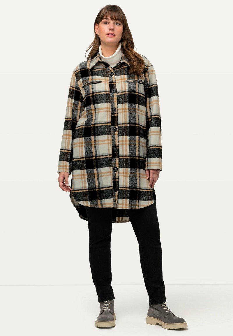 Karierte Jacke in Beigetönen, Schwarz und Orange. Mit Knopfleiste vorne, zwei Brusttaschen und einem leicht längeren Rückenbaum.