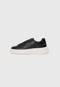 Black leather sneaker with a textured finish, featuring a white platform sole, black laces, and a triangular logo patch on the side.