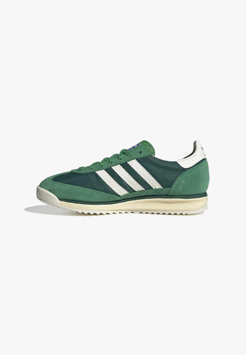 Green sneaker featuring a combination of suede and fabric, with three white stripes, a textured sole, and a contrasting white heel.
