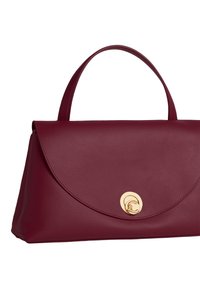 Bordeaux leren handtas met een afgeronde flap, een gladde textuur, gestructureerde vorm en een gouden cirkelvormig hardware detail aan de voorkant.