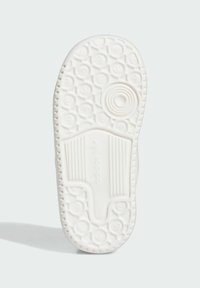 White sneaker sole with a textured bottom featuring circular patterns, ridges, and a smooth central section for traction.