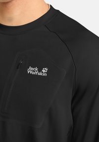Schwarzes Langarmshirt mit einer Reißverschlusstasche auf der Brust. Verfügt über ein Logo, eine glatte Textur und ein tailliertes Design.