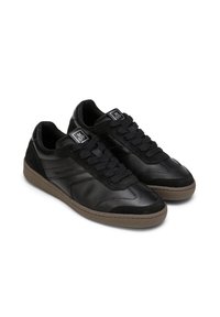 Schwarze Sneakers aus Leder und Wildleder, mit einer strukturierten schwarzen Gummisohle und schwarzen Schnürsenkeln. Mit Logo-Patches auf der Zunge akzentuiert.