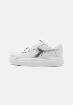Sneakers bianche con tomaia in pelle liscia, dettagli in argento, inserti perforati, lacci piatti e una suola spessa bianca. Logo presente sul lato.