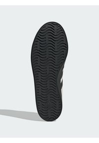 Crni gumeni đon s uzorkom valova, s glatkom stranom i tri bijele pruge na gornjem rubu. Vidljiv je logo marke.