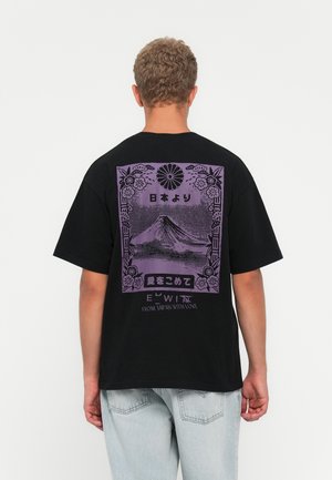 Person wearing black T-shirt with purple graphic of Mount Fuji, floral border, Japanese text, and "FROM JAPAN WITH LOVE" on back.