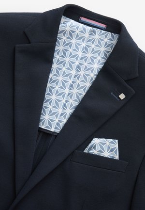 Blazer navy dintr-un material texturat, cu o căptușeală geometrică cu model azul deschis și un batista asortată în buzunarul de la piept.