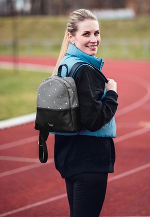 Grau- und schwarz gepunkteter Rucksack aus Stoff, mit abgerundetem Design und verstellbaren Trägern, auf dem Rücken getragen.