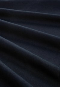 Tissu bleu marine foncé avec des plis doux et une surface lisse légèrement texturée.