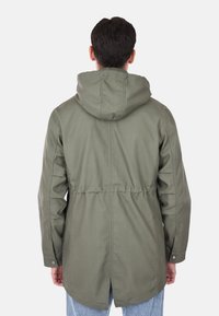 Parka verde oliva con cappuccio, vita regolabile, maniche lunghe e taglio dritto. Realizzata in tessuto resistente con dettagli in bottone.