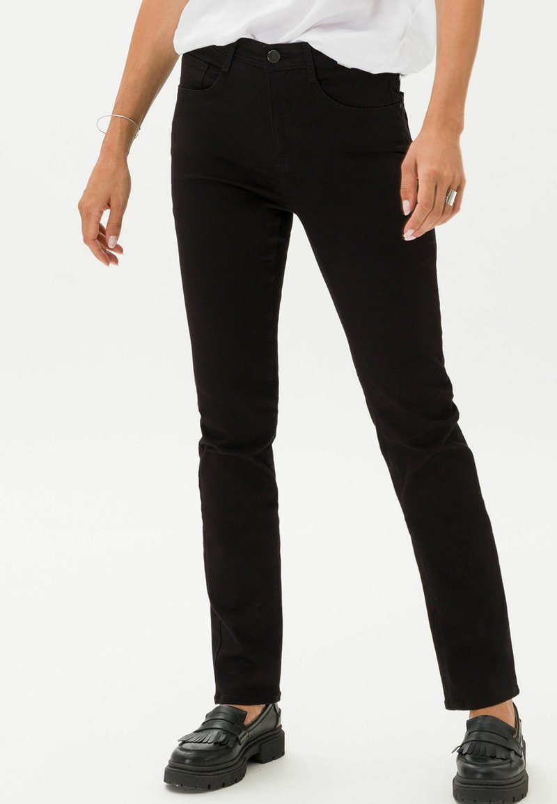Schwarze, schmale Jeans aus Baumwollmischung bieten ein klassisches Design mit fünf Taschen und einem mittelhohen Bund. Getragen mit schwarzen Loafers.