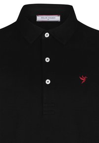 Must musta särk tekstureeritud kangast, kolm valget nööpi ja vasakul rinnal punane tikitud kolibri logo.