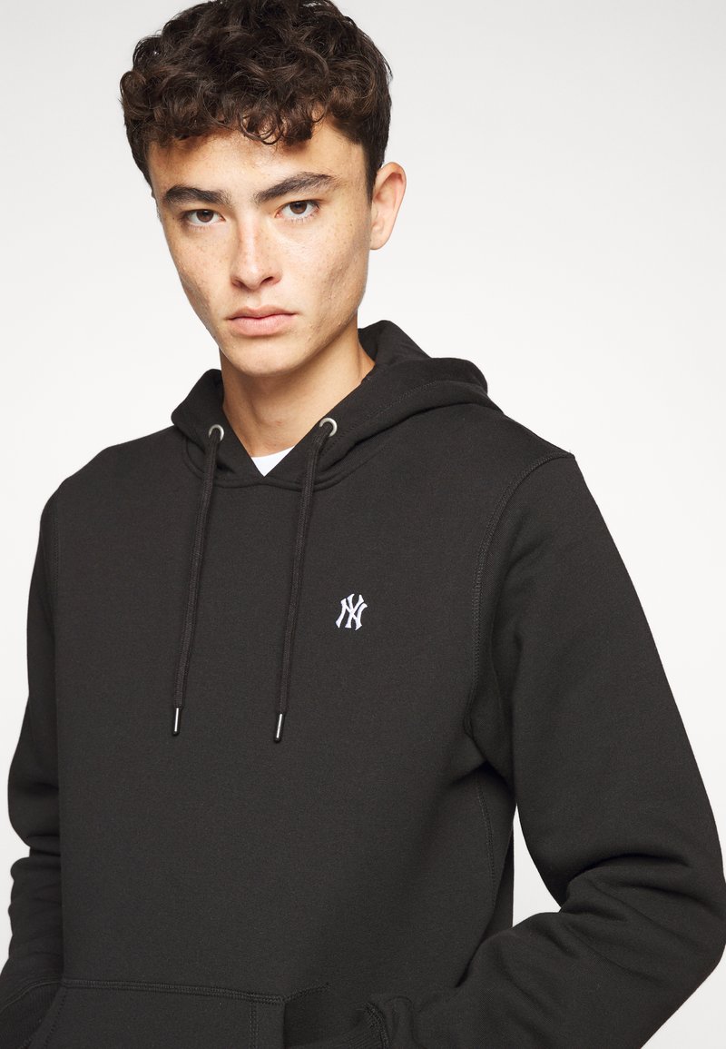 Zwarte hoodie met een voorzak in kangoeroestijl, koordjes en een klein wit logo op de linkerborst. Zacht materiaal met een soepele textuur.