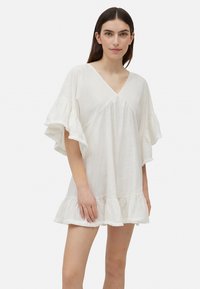 Vestido blanco de manga corta con escote en V, dobladillo con volantes y corte suelto; hecho de una tela ligera y texturizada.