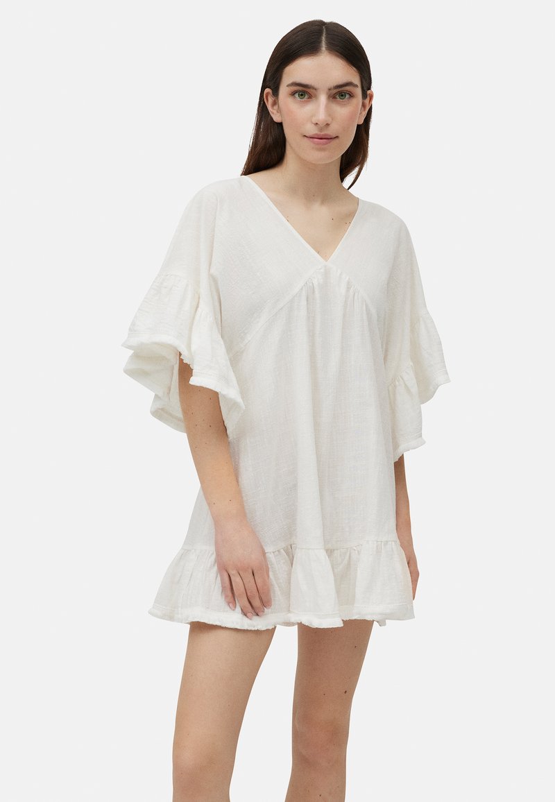 Vestido blanco de manga corta con escote en V, dobladillo con volantes y corte suelto; hecho de una tela ligera y texturizada.