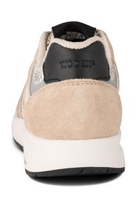 Baskets beige et grises avec une tige en daim et en maille, dotées d'un contrefort de talon noir, d'accents texturés et d'une semelle blanche rembourrée.