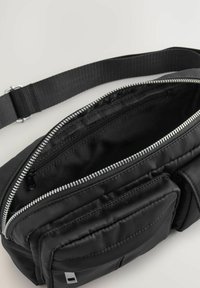 Borsa a tracolla in nylon nero con tracolla regolabile, doppio scomparto principale con zip e due tasche frontali per ulteriore spazio di stoccaggio.