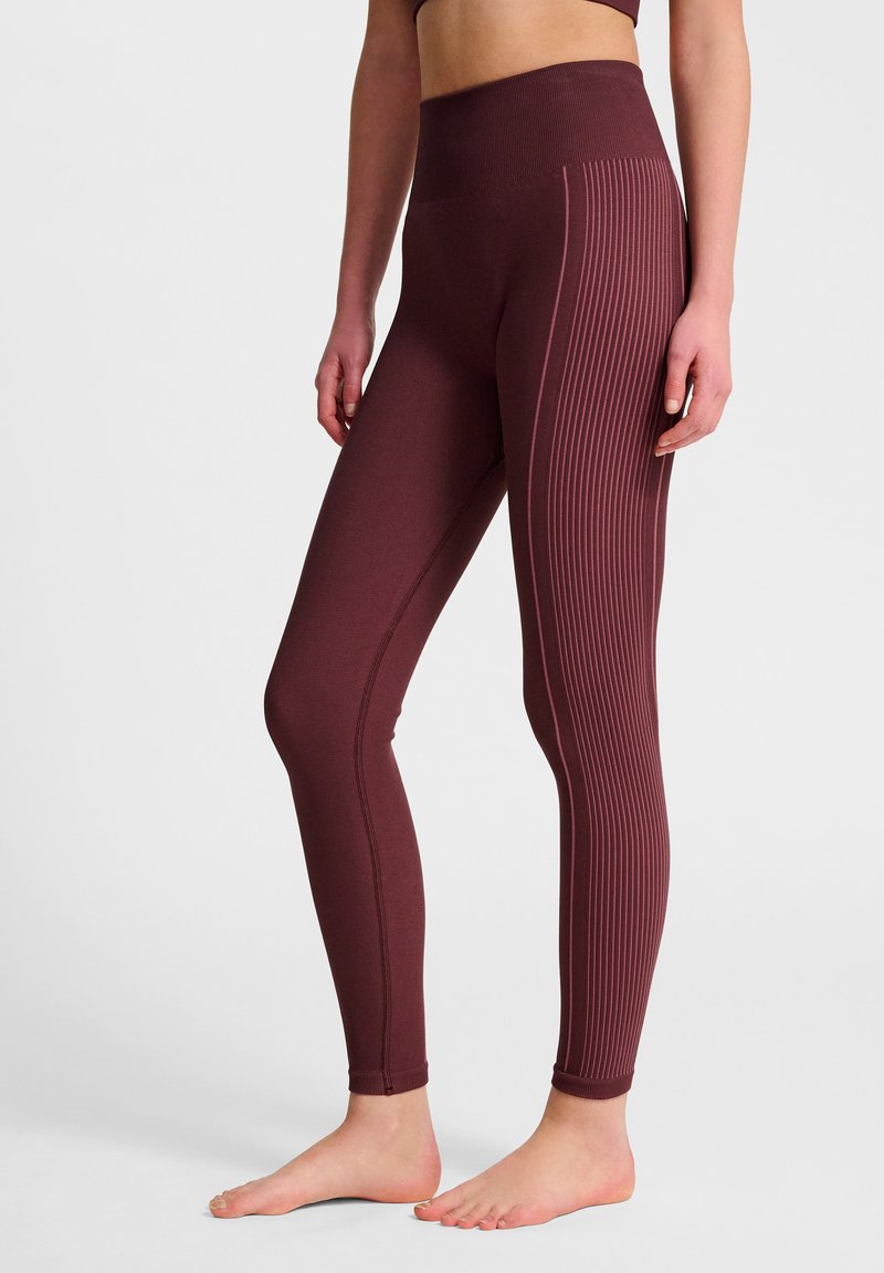Bordeaux legginsy z wysokim pasem charakteryzują się pionowym prążkowanym splotem po zewnętrznej stronie. Wykonane z elastycznego materiału odpowiedniego do odzieży sportowej.