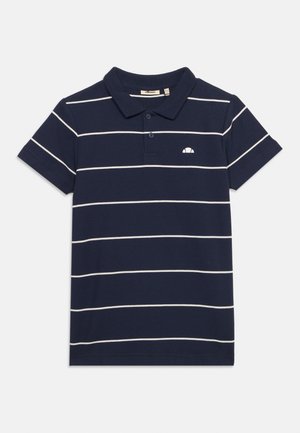 Σκούρο μπλε πολο με κοντά μανίκια, λευκές οριζόντιες ρίγες και μικρό λευκό λογότυπο στο αριστερό μέρος του στήθους, γιακάς με δύο κουμπιά.