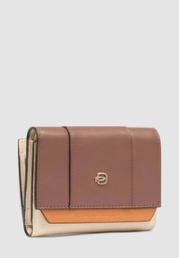 Portafoglio compatto tricolore in pelle con patta marrone, dettaglio arancione, corpo beige e piccolo logo metallico sulla parte anteriore, posato su uno sfondo grigio chiaro.