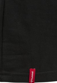 Sort bomulds T-shirt med en tekstureret overflade. Har et rødt syet mærke i kanten med mærkenavnet "hummel." Simpelt design.